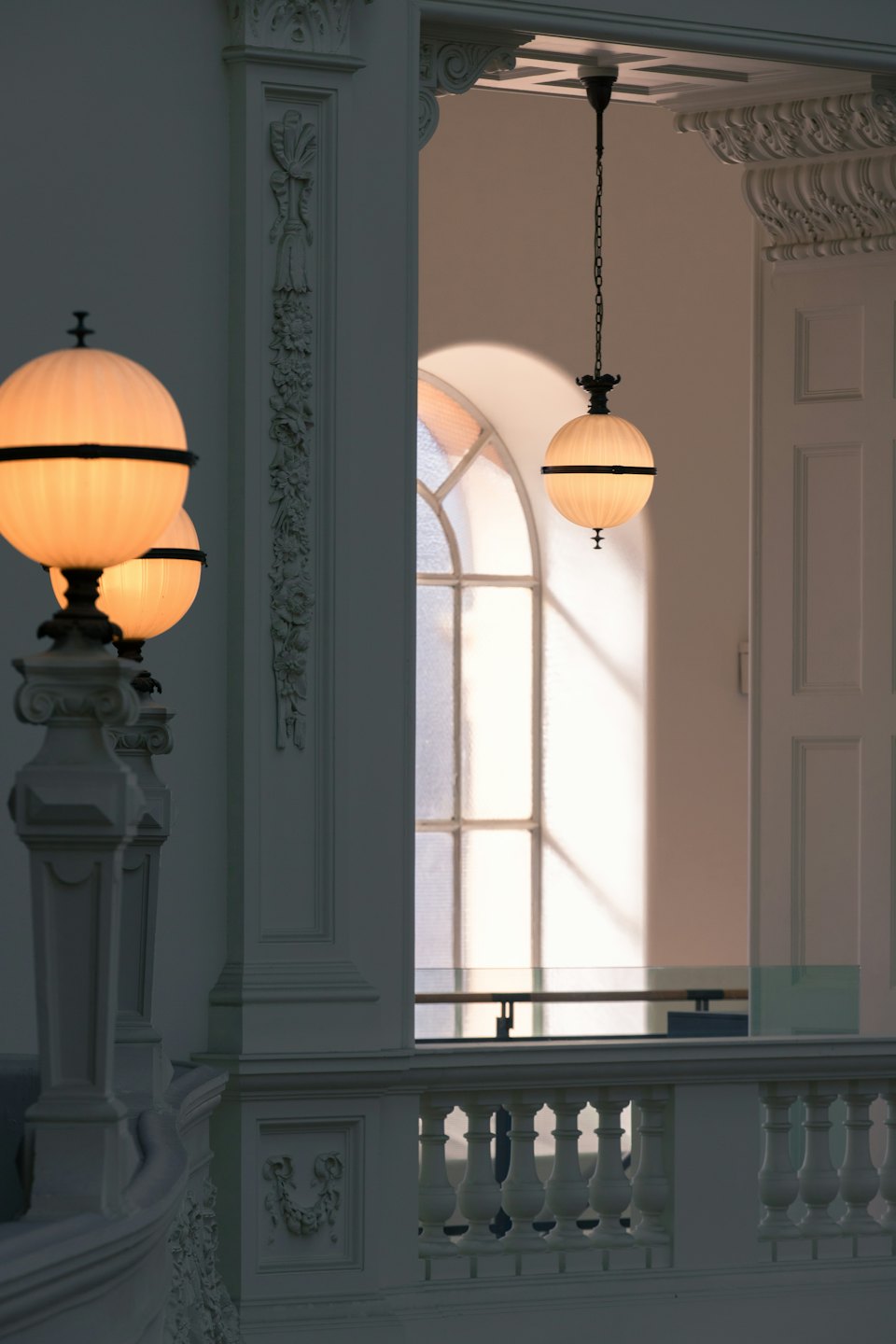 Interno con balaustre bianche, colonne e finestra ad arco.